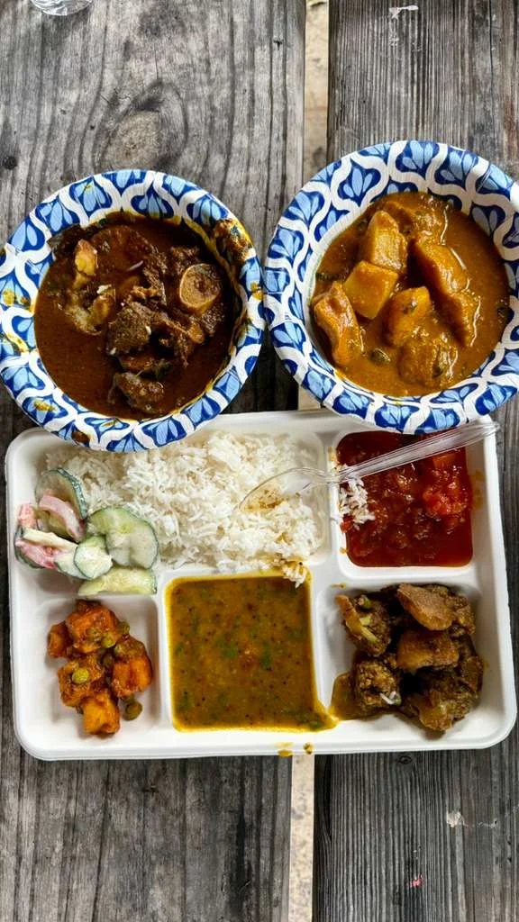 A picnic meal with rice, dal, vegetables, and curry served on a tray and in bowls